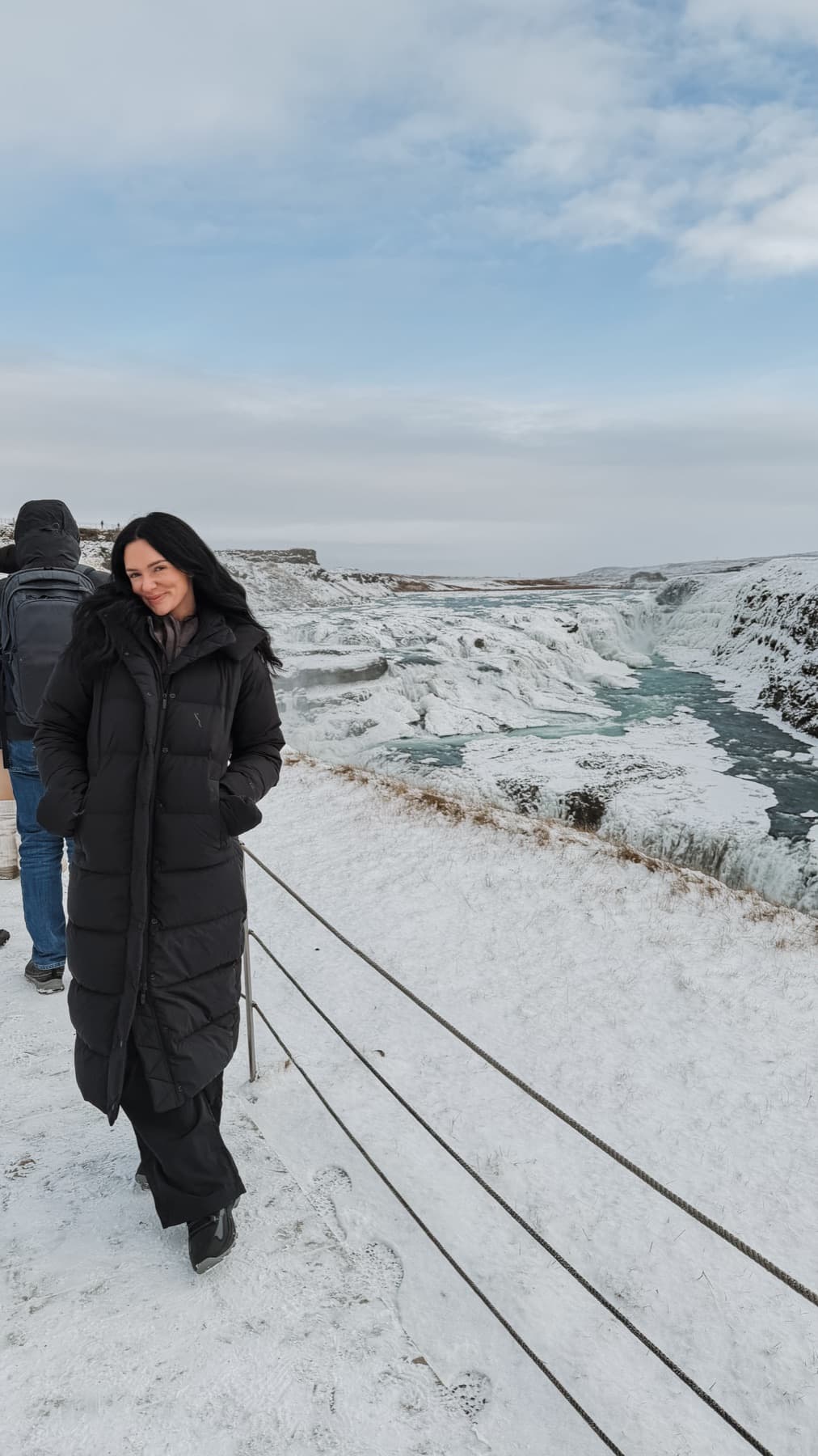 Nikki in a black coat at a frozen waterfall